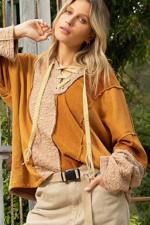 Lace Up Color Block Knit Top Designed in drawstring lace up with hood Long sleeves Oversize fit Out seam detailing Color blocked vintage wash knit panels Floral pattern quilted knit top